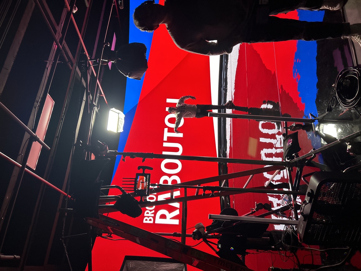 Camera, lighting, crew and athlete framed against the red and blue LED studio wall